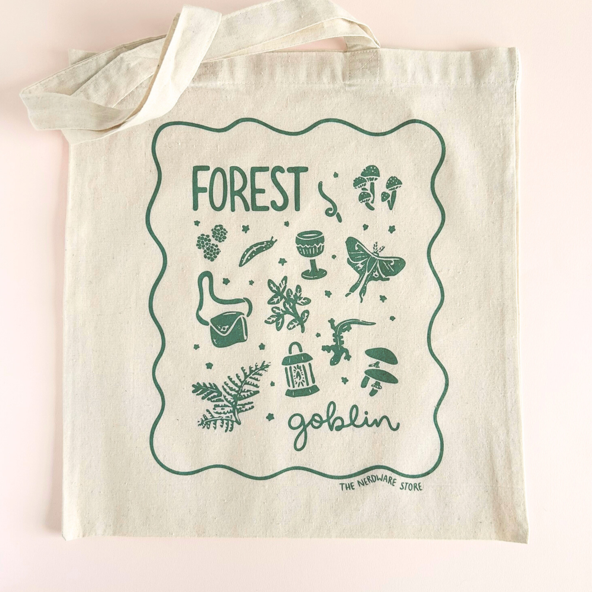 tote bag with designs in dark green that say forest goblin with fantastical illustrations of a slug, a goblet, a satchel, foliage, a lantern, mushrooms, and a luna moth