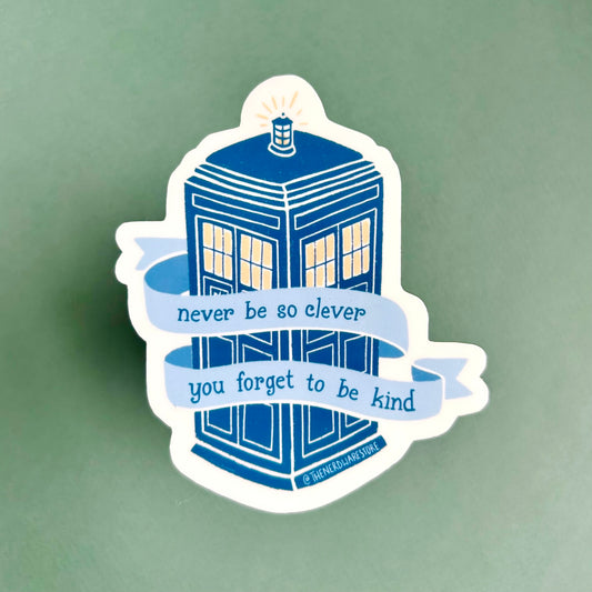 A large vinyl decal sticker of the Tardis from Doctor Who with words on a banner that say "never be to clever you forget to be kind."