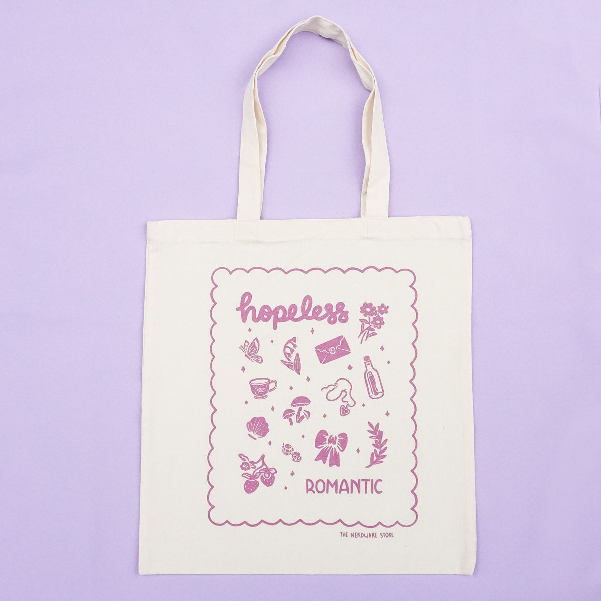 tote bag with illustrations in purple that say hopeless romantic with romantic flowers, a butterfly, mushrooms, strawberries, and a scalloped border