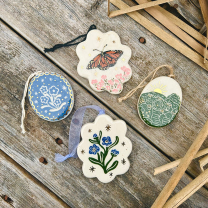 Four delicate floral and nature-themed ceramic ornaments with gold and scallop edged details.